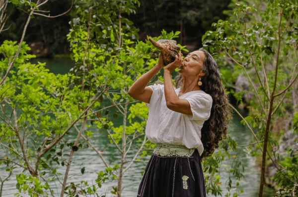 woman blows into shell horn at mayakoba spa during wellness treatment